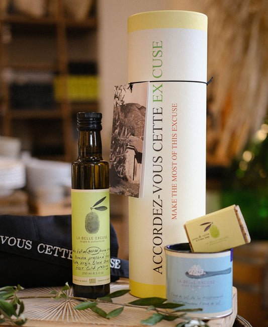 La Belle Excuse gourmet gift set featuring 250 ml black olive oil, Mediterranean fleur de sel, a unisex kitchen apron, and rosemary, lemon and coffee kitchen soap.