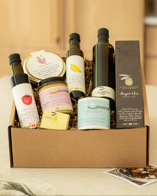 A curated La Belle Excuse gourmet gift box featuring organic Agorelio olive oil, lemon and raspberry white balsamic vinegars, French shallot confit, roasted garlic mustard, Mediterranean fleur de sel, and rosemary, lemon and coffee kitchen soap.