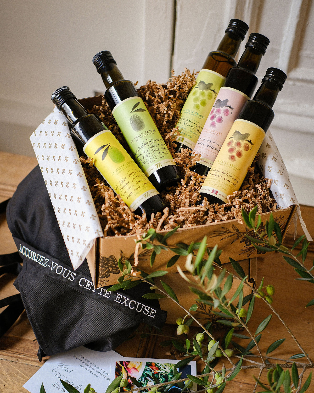 La Belle Excuse The Basics Gift Set : green and black extra virgin olive oils, white and traditional balsamic vinegars, red wine vinegar, and a kitchen apron.
