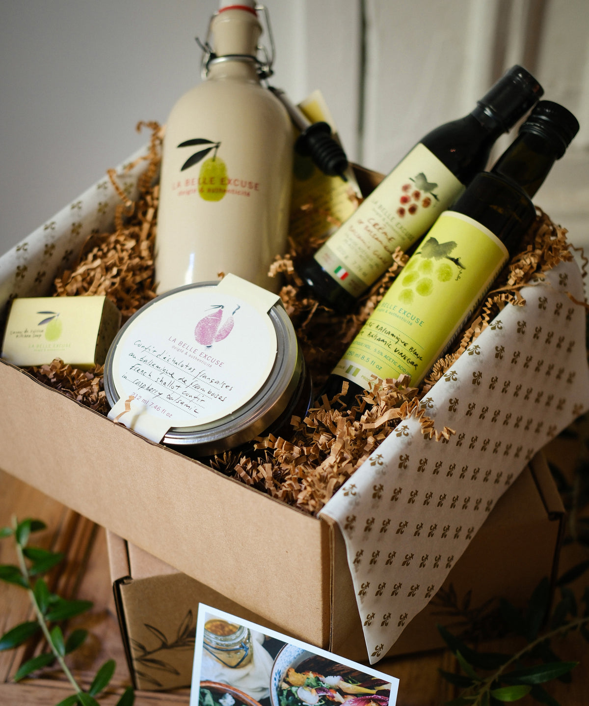 La Belle Excuse Host & Hostess Gift Set featuring a ceramic decanter with 500 ml of green extra virgin olive oil, 250 ml balsamic vinegar, balsamic glaze, and a jar of confit.