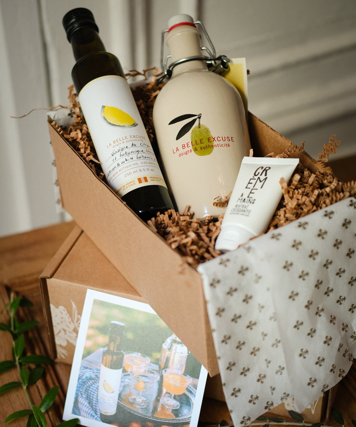 La Belle Excuse “From Us!” Gift Set featuring a ceramic cruet, extra virgin green olive oil, lemon and white balsamic vinegar, and travel-size refreshing hand cream.
