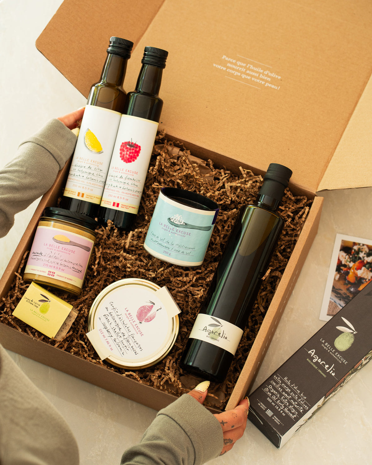 A curated  La Belle Excuse gourmet gift box featuring organic Agorelio olive oil, lemon and raspberry white balsamic vinegars, French shallot confit, roasted garlic mustard, Mediterranean fleur de sel, and rosemary, lemon and coffee kitchen soap.