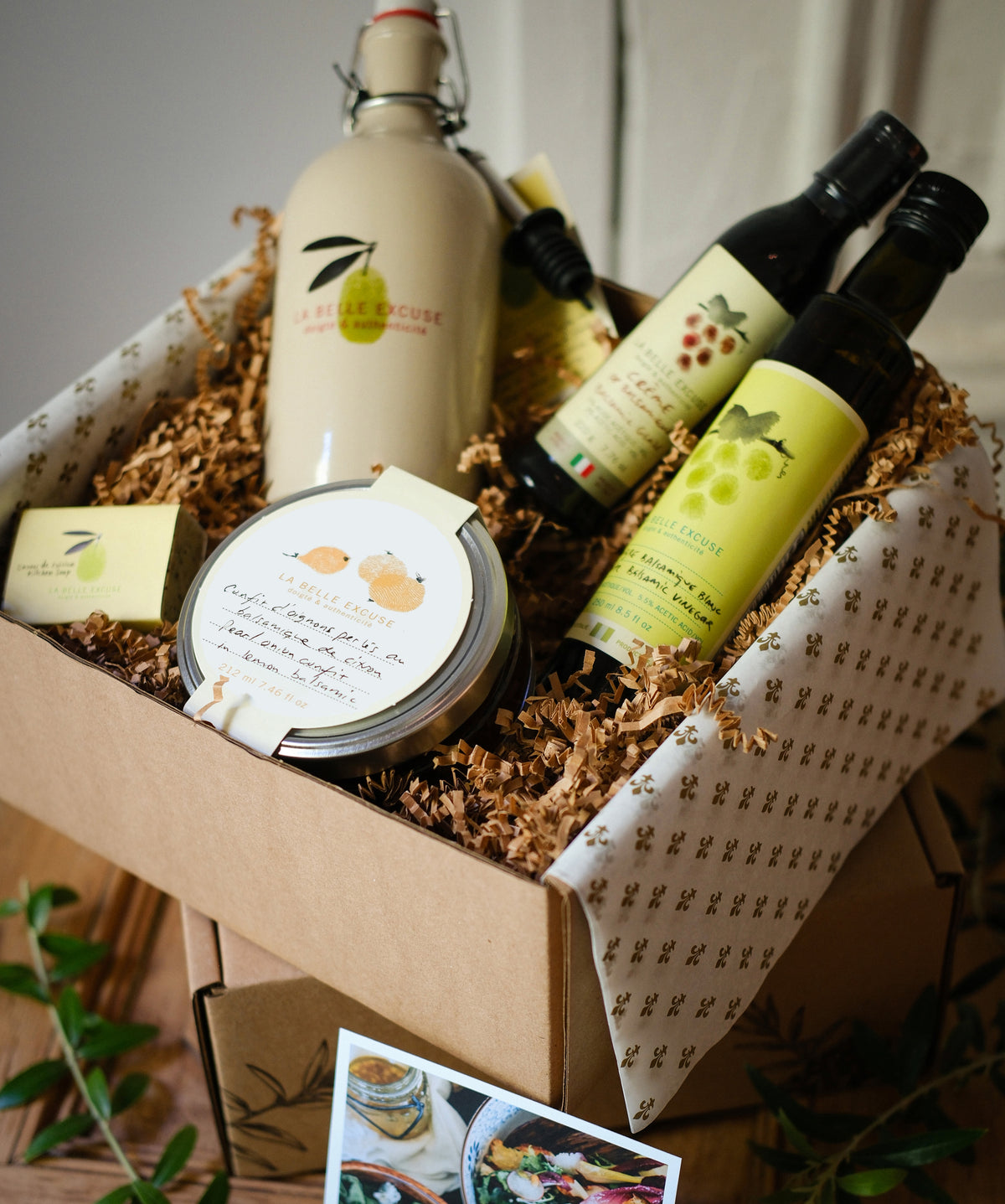 La Belle Excuse Host & Hostess Gift Set featuring a ceramic decanter with 500 ml of green extra virgin olive oil, 250 ml balsamic vinegar, balsamic glaze, and a jar of confit.